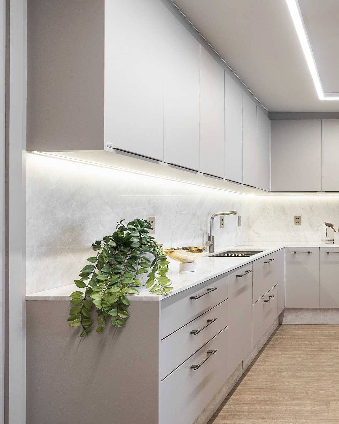 Cozinha linear clara com bancadas contínuas e iluminação embutida elegante.