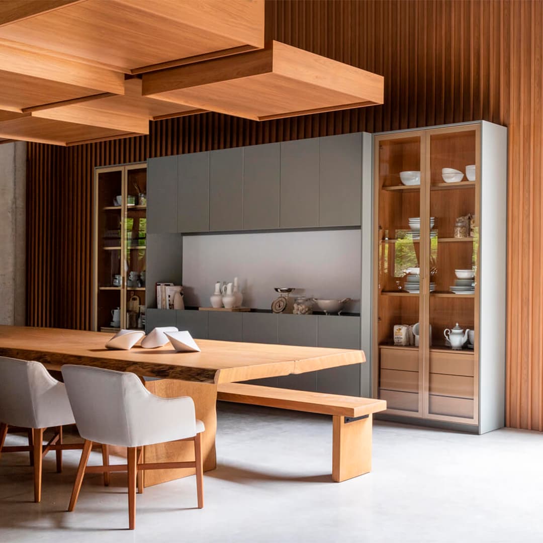 Sala de jantar com teto ripado em madeira, cristaleiras e mesa em madeira maciça.