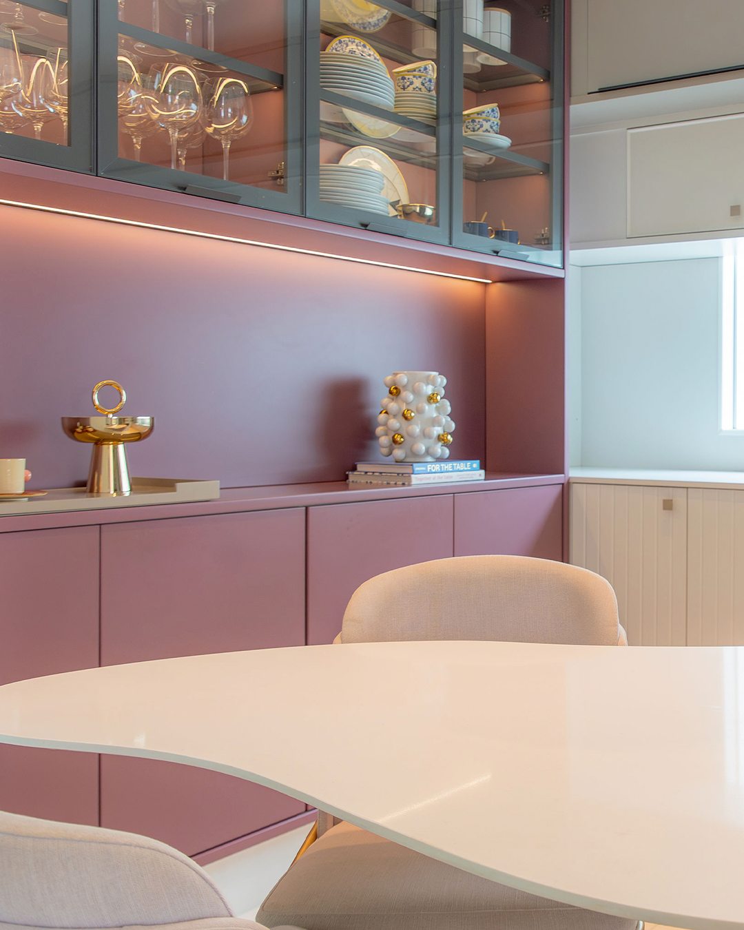 Ambiente com vitrine rosé, iluminação linear e linguagem contemporânea de alto padrão.